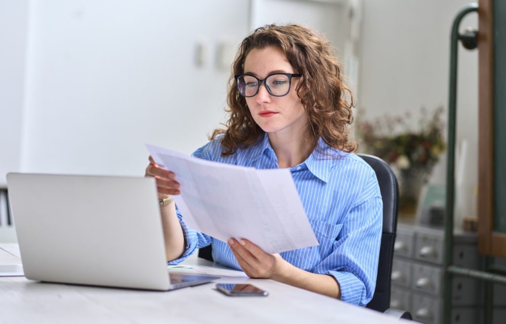 Professional reading a document while working on laptop